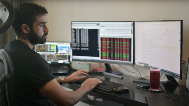 a man sitting at a desk with multiple monitors